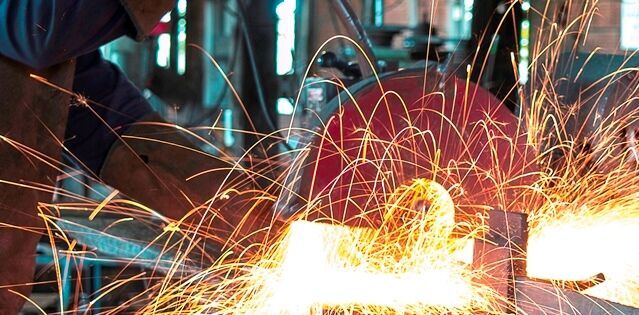 Bright orange sparks flying from a piece of metal that is being cut.