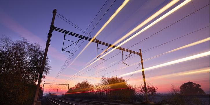 Train tracks at dusk with light trails showing movement of a high speed train