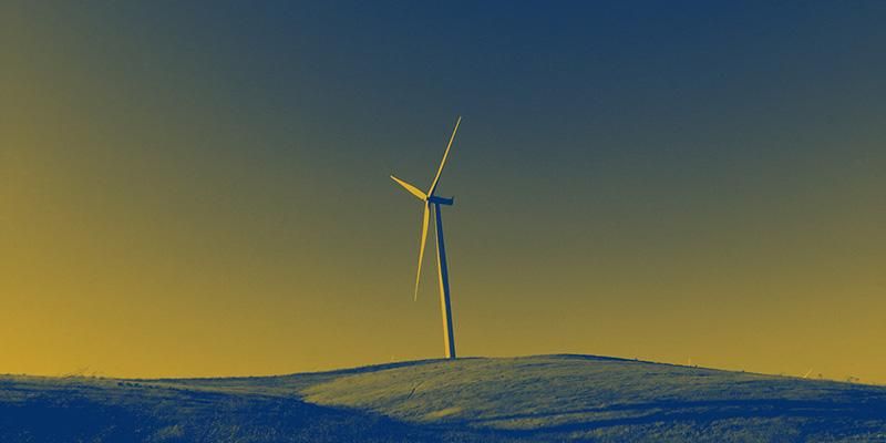A duo tone image in the colours of COP27, yellow and blue, featuring a solitary wind turbine on a hill.