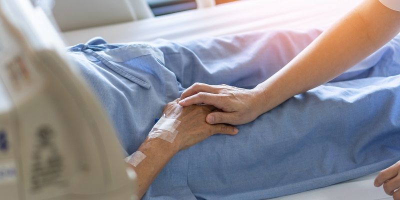 Patient having his hand held in hospice bed