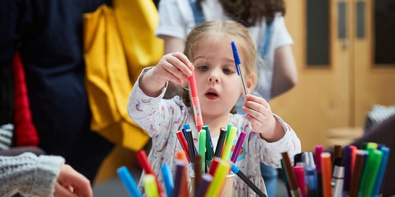 A child holding coloured pens at Be Curious 2020