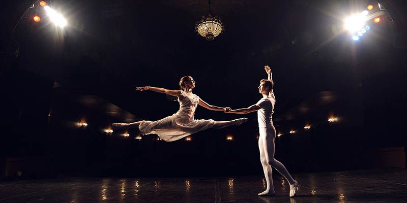 View from backstage into an theatre auditorium of two ballet dancers during a performance.