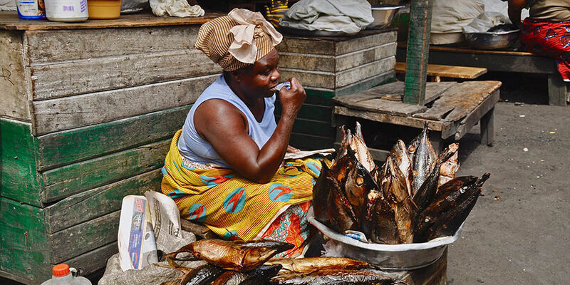 A West African fishmonger selling dried fish in a market.