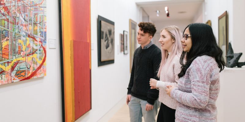 Three students looking at art in a gallery