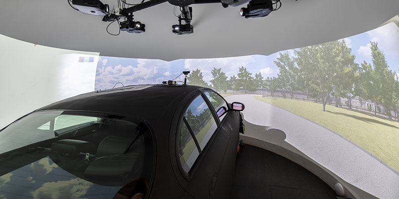 Inside a driving simulator, showing a vehicle and computer generated view of a road