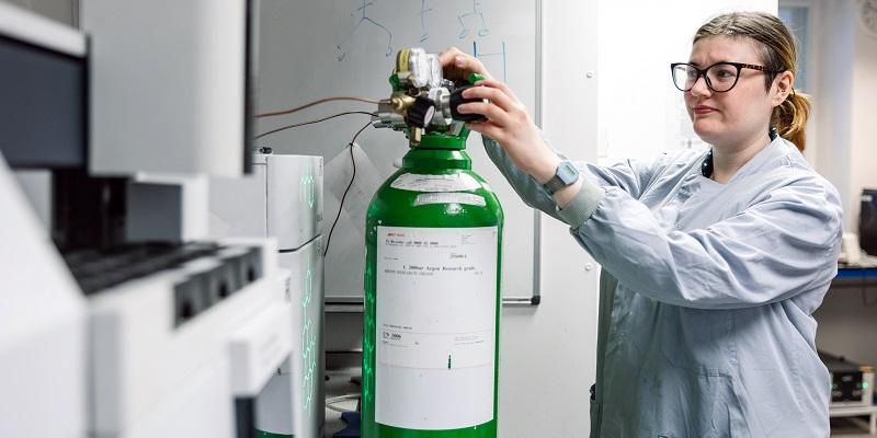 A scientist adjusts a valve on a gas bottle in a bioenergy lab