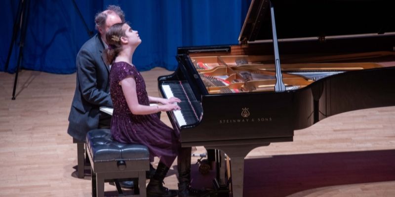 Lucy Illingworth plays a grand piano in the Clothworkers Hall, sat next to her teacher Daniel Bath