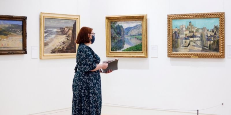 woman looking at paintings in gallery