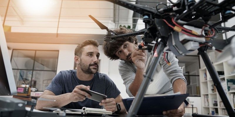 An engineer and a technician working together on a drone in an office