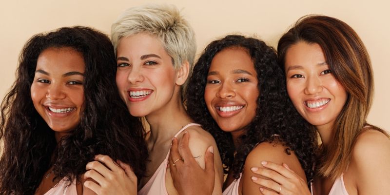Four women with different skin tones looking at the camera