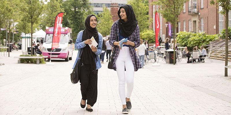 Two students walking together on an open day outside Leeds University Union.