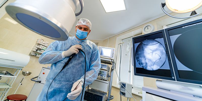 A healthcare professional prepares a colonoscopy instrument before examining a patient.