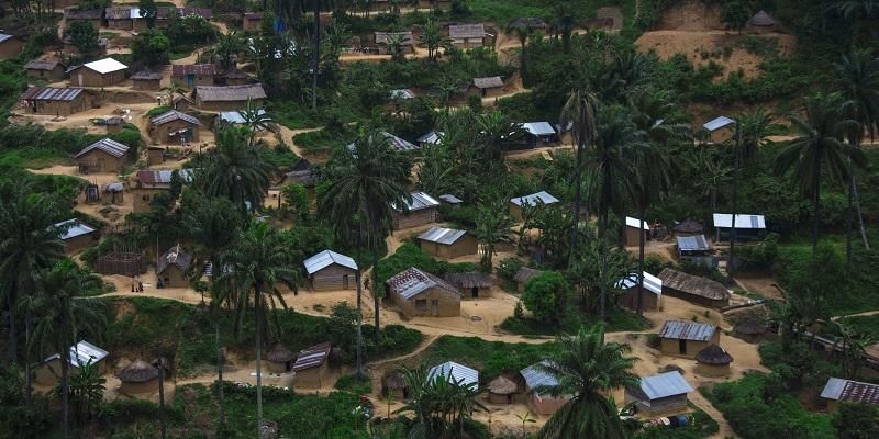 This is an aerial image of an African village showing small buildings on the side of a sandy track. There is no sign of major infrastructure development.