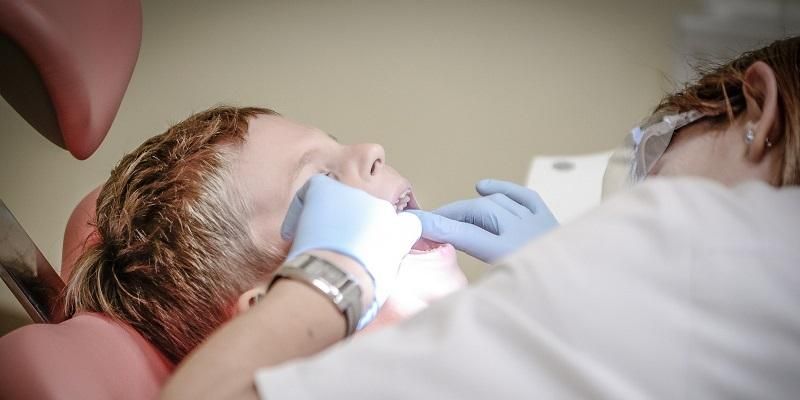 Image shows a dentist looking into a child's mouth as part of a dental examination.