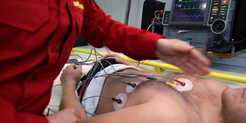 The image shows a patient have a heart trace test in the back of an ambulance