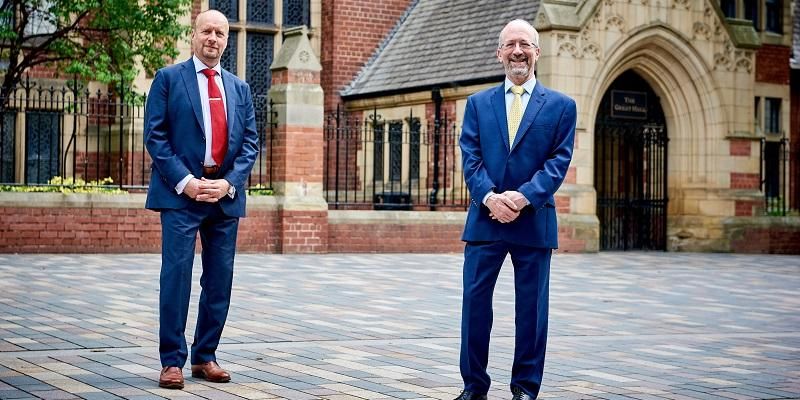 The image shows two men outside the Great Hall on the University of Leeds campus. Professor John Ladbury is on the left - Professor David Sebag Montefiore is on the right