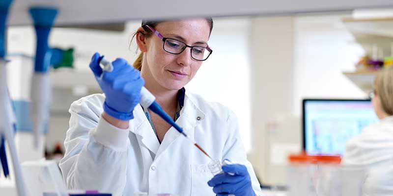 Scientist in lab coat carrying out work in a laboratory.
