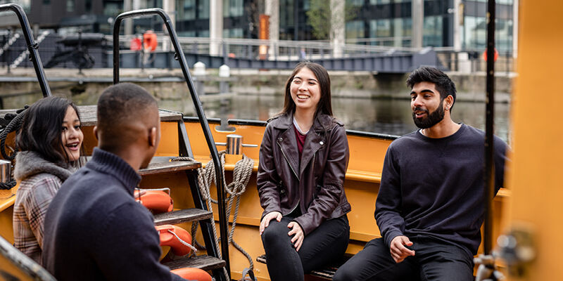 Four students smiling inside a yellow boat.