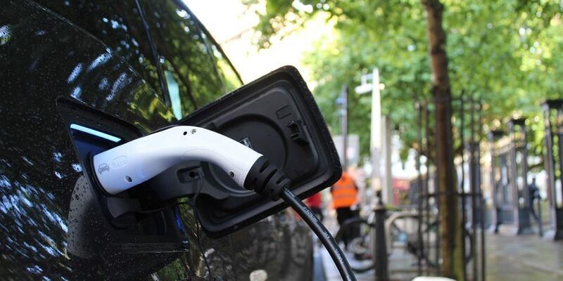 Close up of electric car charging with tree in background