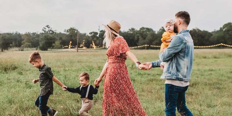 A family,- man, woman and three children - walking through a field