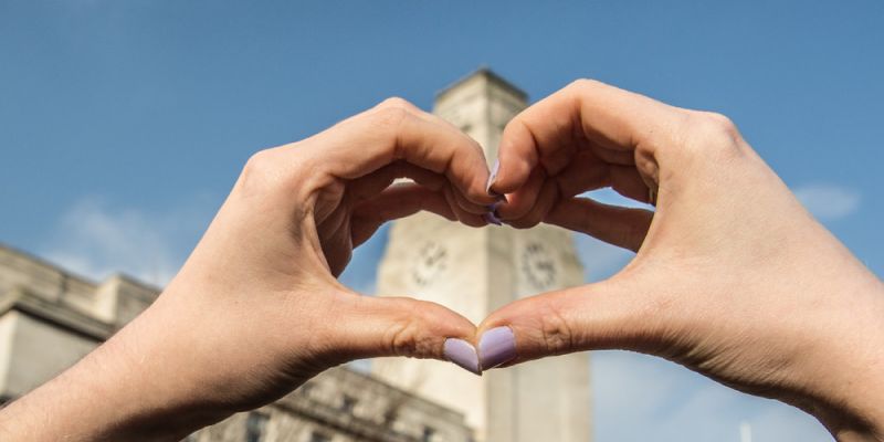 Hands form the shape of a heart in front of the Parkinson tower
