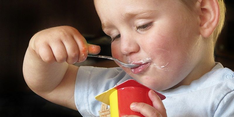 young boy eats yogurt