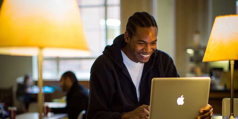Student laughs while sitting at laptop