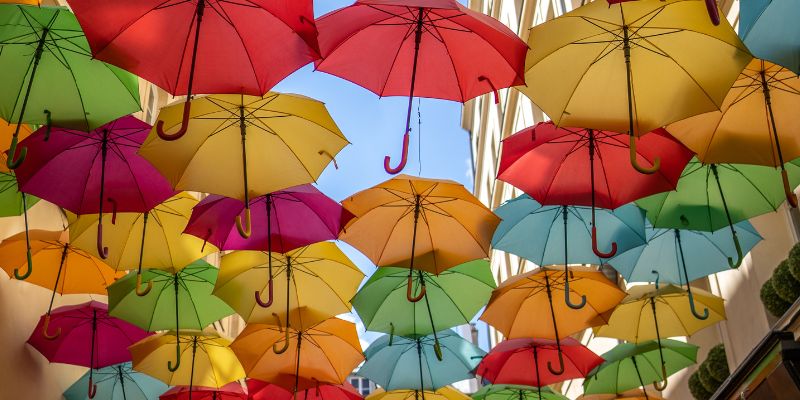 Multiple coloured umbrellas under a blue sky
