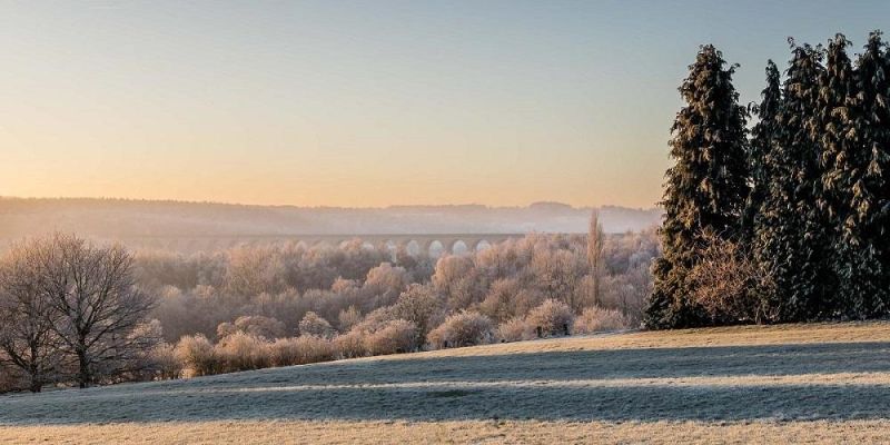 The Crimple Valley viaduct, viewed from across fields and treetops on a frosty day