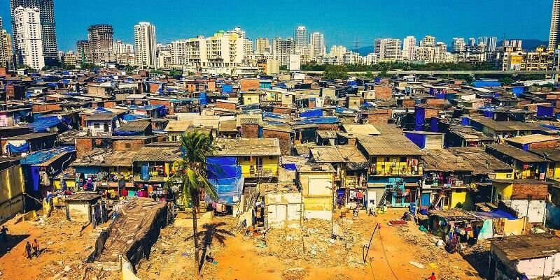 The image shows the contrasting city scapes in Mumbai: high rise luxury and low rise slums