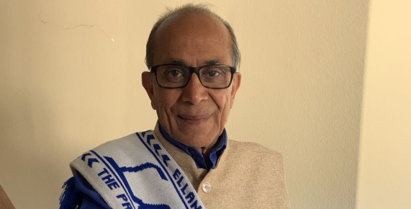 Madan Luthra wearing a white and blue Leeds United FC scarf.